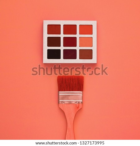 Trend photography on the theme of the actual colors for this season - a shade of orange. Professional multi-colored eye shadow palette on a light background.