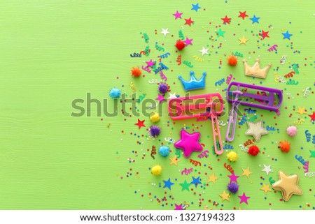 Purim celebration concept (jewish carnival holiday) confetti and noisemaker over wooden green background