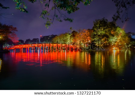 Landmark of Hanoi - "The Huc Bridge" in the night, It small bright red wooden bridge across Hoan Kiem Lake to Ngoc Son Temple at Hanoi, Vietnam. Royalty-Free Stock Photo #1327221170