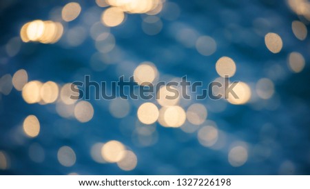 Glistening and shimmering blue blurred ocean surface at sunset or sunrise with sun reflections on it