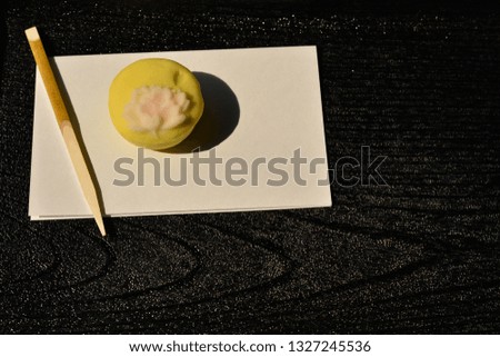 Japanese traditional confectionery cake "wagashi" on the black wooden tray with wooden stick in Japanese garden cafe.
