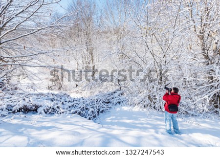 Nature photographer in snow covered winter garden