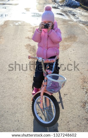 girl in a pink jacket on a bicycle in the spring with a camera