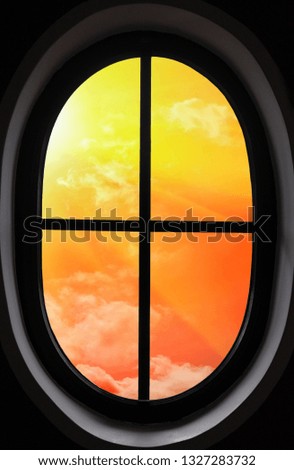 view of the orange sunset through the oval window in a dark room