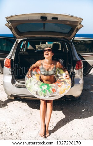 Pretty pan asian brunette with float near car trunk at the seaside beach