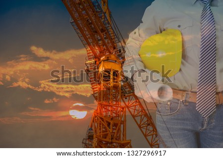 Double exposure of Engineer with safety helmet and drawing with tower crean and the sunset is background.