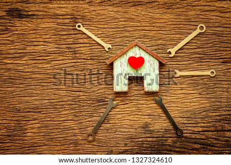 Wooden house with red heart and wrench put on the old wood background, Loan for construction real estate and renovate the new home for family concept.