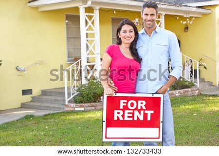 Couple Standing By For Rent Sign Outside Home