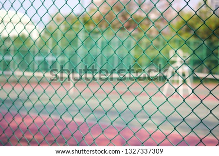 metal net with blur photo of tennis court in public park.