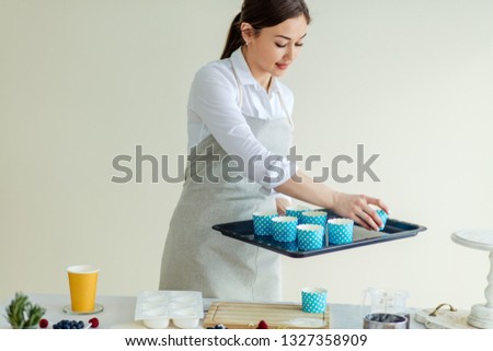 attractive girl putting cupcake liner on the oven sheet at home kitchen. close up photo.