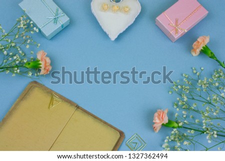 top view vintage book with empty sheets , gift boxes and flowers on a pastel blue background
