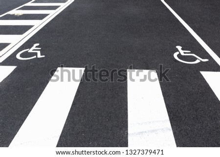 Disabled sign painted on grey asphalt. 