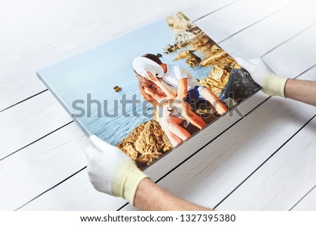 Photography printed on canvas with gallery wrap method of canvas stretching. Photo of kissing couple in love is in male hands