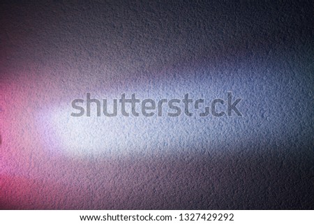 On a purple textural background, a bright ray of light and a pink glow