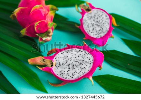 Closeup on turquoise background dragonfruit, tropical fruit, palm leaves, fashionable, bright picture, fitness, healthy lifestyle, colors