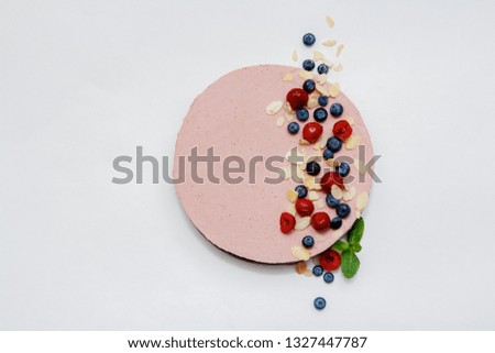 Cake with whipped pink cream, blueberries, blackberry and raspberry on white background. Top view. Picture for a menu or a confectionery catalog