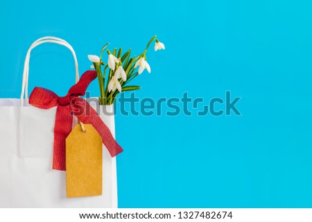 A bouquet of snowdrop flowers in a paper bag with price label note .Seasonal spring shopping. Holiday sale. Preparing for the end of winter. Easter mood.