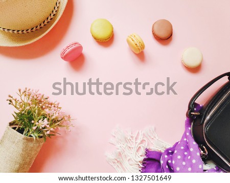 Flat lay photo parisian style items. French atmosphere and mood. Sun hat, flowers, small bag, purple scarf and many delicious macaroons. Mockup for fashion blog