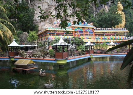 Pond with artificial waterfalls, bridges and gazebos for relaxing on the background of a Hindu temple in the Batu caves complex