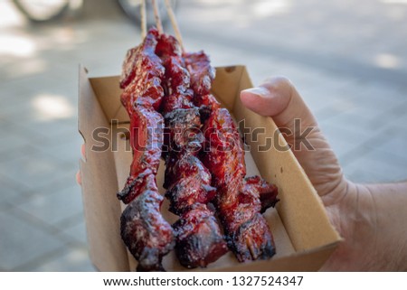 A man purchases delicious marinated barbecued kebabs in a cardboard biodegradable takeaway container at a food market in Christchurch, New Zealand