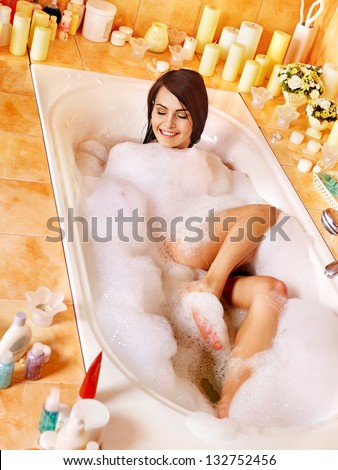 Woman relaxing at water in bubble bath.