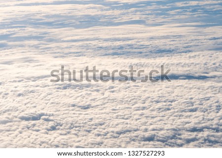 Background of beautiful fluffy natural white clouds texture with blue sunset sky shoot from window of airplane flight fly above with top view cloudscape. Present freedom holiday travel journey