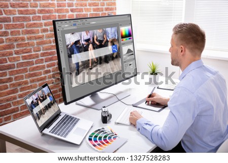 Male Designer's Hand Using Graphic Tablet While Working On Multiple Computers