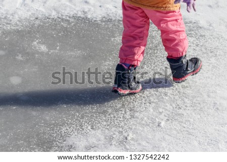 Small child. ride on the ice. he has no skates. close-up.