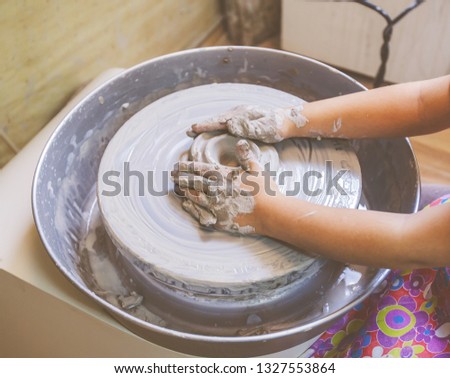 hands of young artist shaping clay on pottery wheel at workshop in ceramic studio 