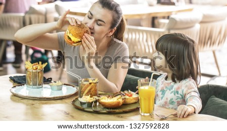 Loving family. Mom with cute daughter eating fast food in a cafe, family and nutrition concept