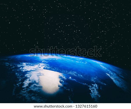 Earth view from space. Clouds and glow above. Stars and galaxy in the distance. Elements of this image furnished by NASA.