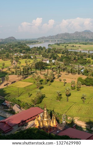 Vertical picture of golden pagoda, local vegetation and Thanlwin Bridge in Hpa-An, Myanmar