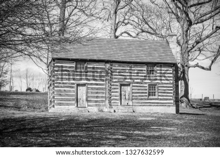 Old Black and White Log Cabin with Trees in background