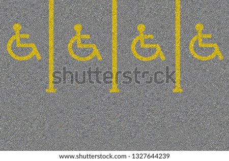 Yellow Disabled sign on a empty parking lot. Black tarmac texture with road marking
