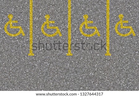 Yellow Disabled sign on a empty parking lot. Black tarmac texture with road marking