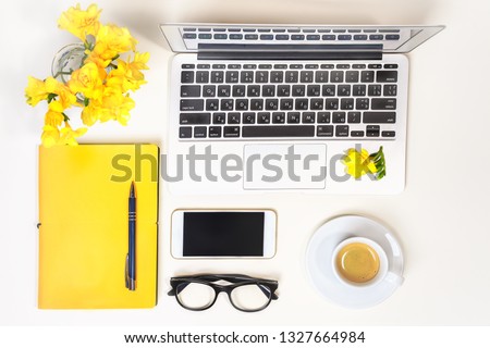 Women's home office desk. Workspace with laptop, computer, yellow notebook, fashion glasses, cup of coffee, mobile phone, flowers on white background. Concept online shopping. Concept  Color 2021.