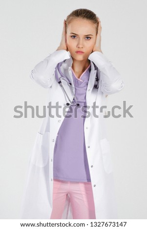 Girl doctor blonde young light studio background beautiful day one put her hands on ears. Bad time at work problems with boss wrong reform.