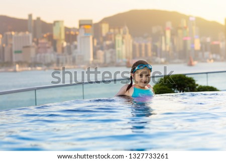 Children swimming in roof top outdoor pool on family vacation in Hong Kong. City skyline from infinity pool in luxury hotel in China. Kids swim and enjoy skyscraper view in Asia. Travel with child.