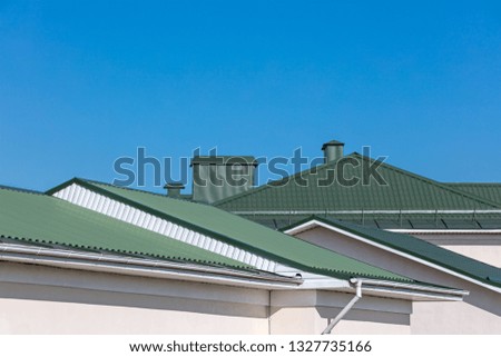 green rooftops of houses with new rain gutters on clear blue sky background