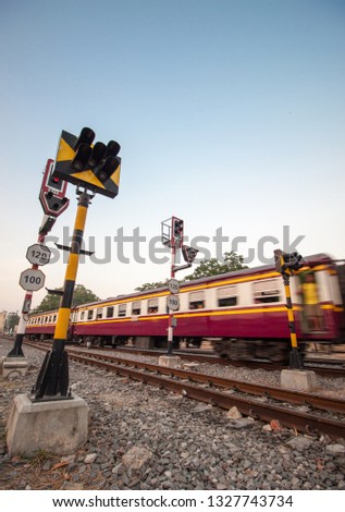 Stop signal for railway junction. railroad crossing sign warning lights. Blur of Procession train led by Yellow Diesel electric Locomotives and sail through rail chopper with traffic light/speed limit