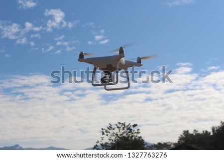 White drone fly in the blue sky and had beautiful white clouds. It was a very sunny daylight daytime.
