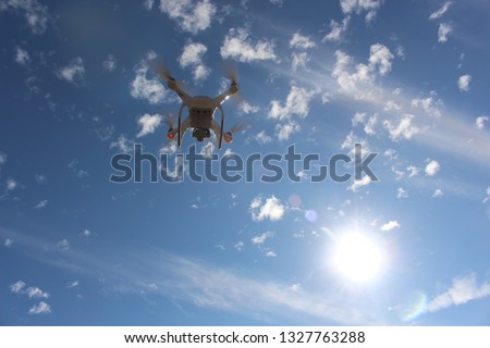 White drone fly in the blue sky and had beautiful white clouds. It was a very sunny daylight daytime.