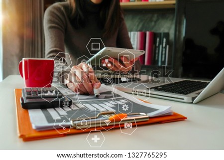 businesswomen or Designer using tablet with laptop and document on desk in modern office with virtual interface graphic icons network diagram.