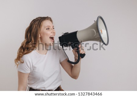 Picture of nice young woman in a white t-shurt screaming into megaphone in her left hand.