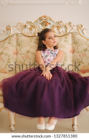 Little girl sist on a sofa. Happy child in stodio. Little model