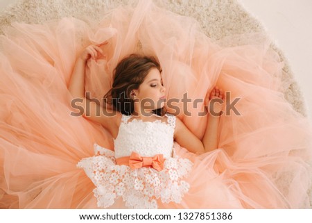 Photo of little girl in studio. Little beautiful girl with brown hair in a Peach-colored dress