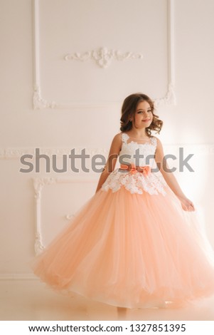 Happy little princess in beautiful dress walk though the big studio. spin around