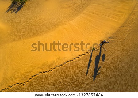 Aerial view of Woman carrying basket and children at sunset in Bau Trang sand dune, Mui Ne, Binh Thuan, Vietnam