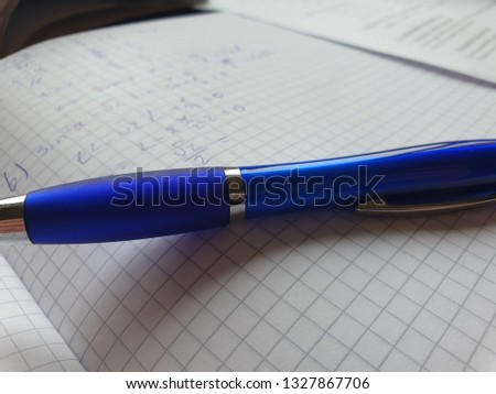 Blue pen on the background of a notebook in a cage, work on the bugs