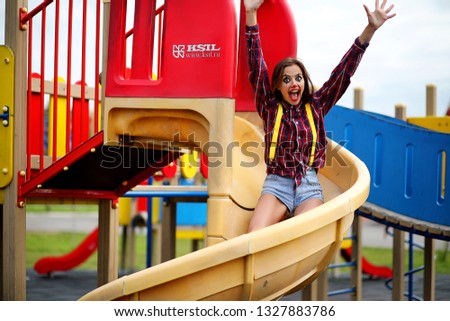 Cute girl in a clown makeup on a background of a fair and steps

